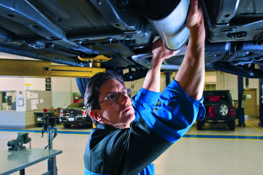 Service technician inspecting a Buick or GMC vehicle during a routine maintenance visit
